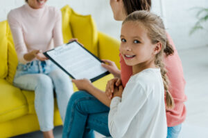 selective focus of child smiling near mother and babysitter at home