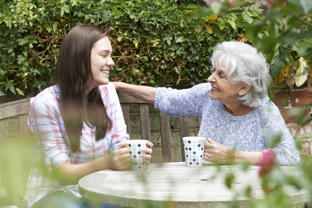 teenage granddaughter relaxing with grandmother in garden