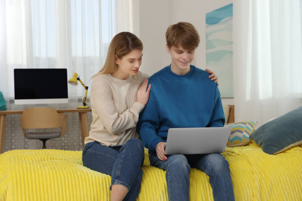 happy mother and her teenage son with laptop at home