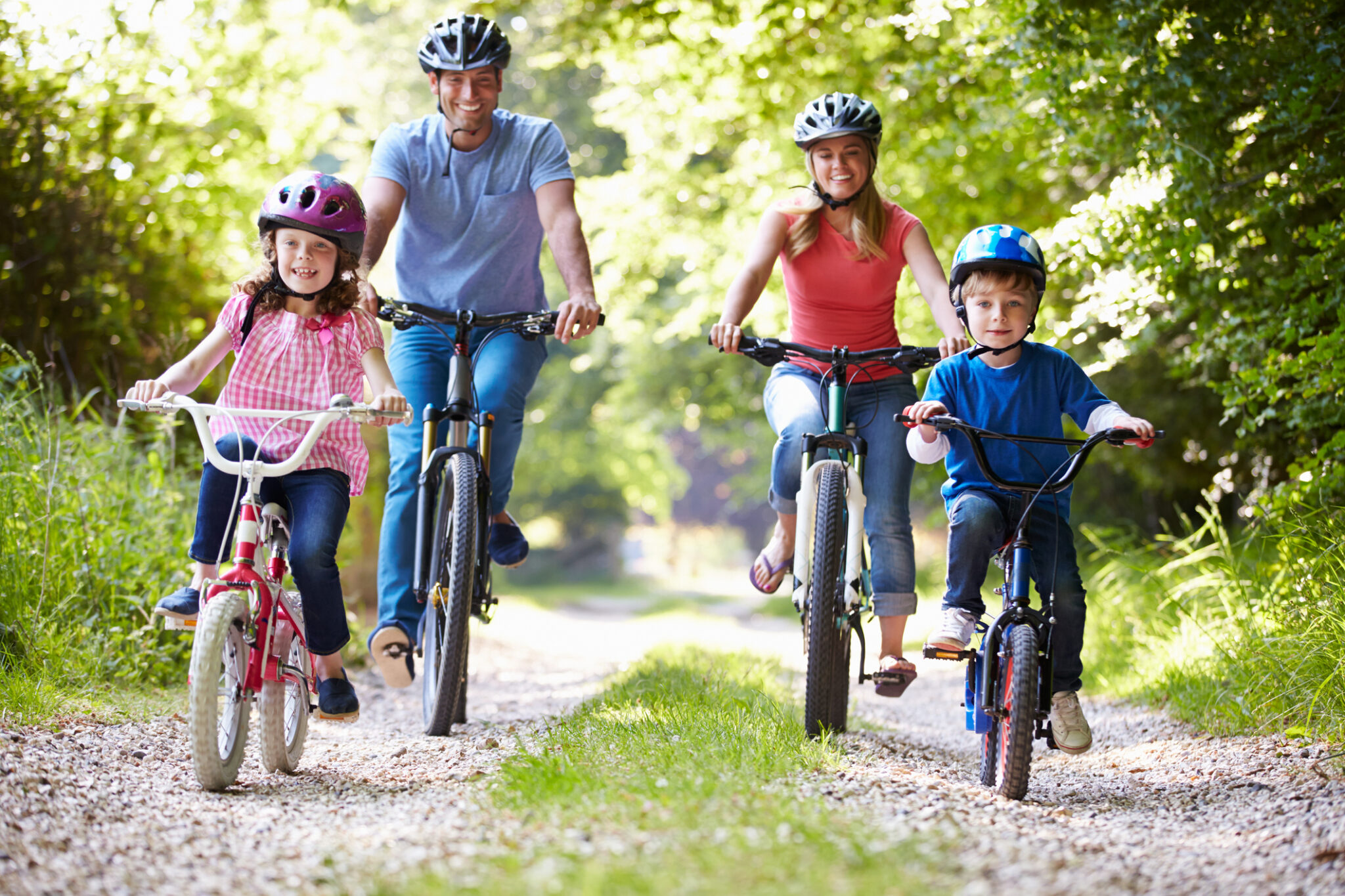 family of four riding bikes on gravel road
