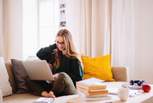 a young female student sitting on sofa, using laptop when studying.