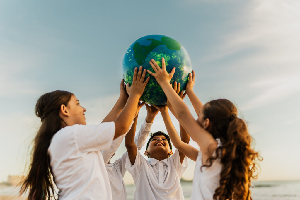 children holding a planet on the beach
