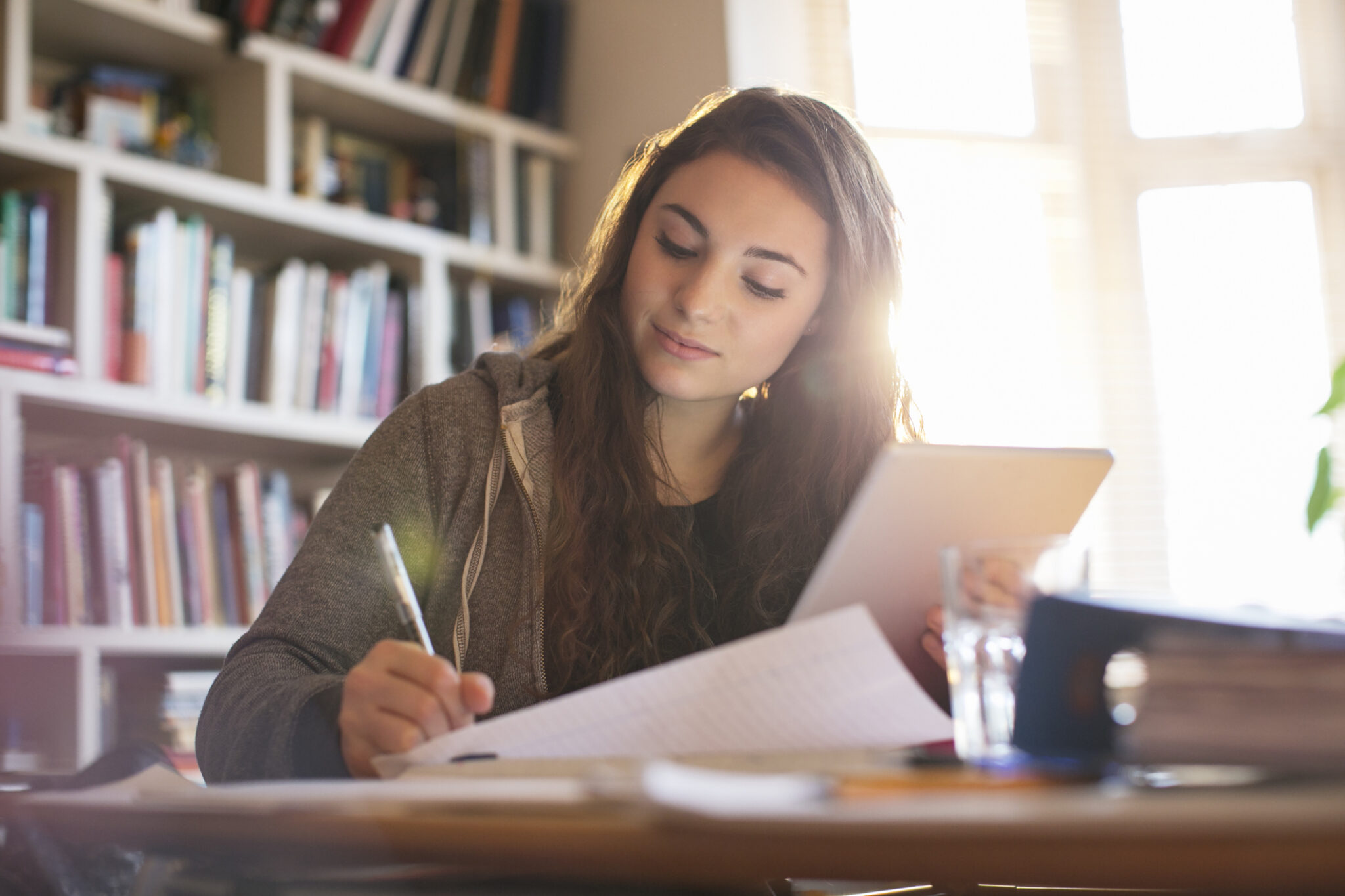 teenage girl with digital tablet doing homework at desk