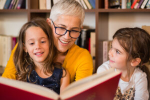 old woman reading to granddaughters