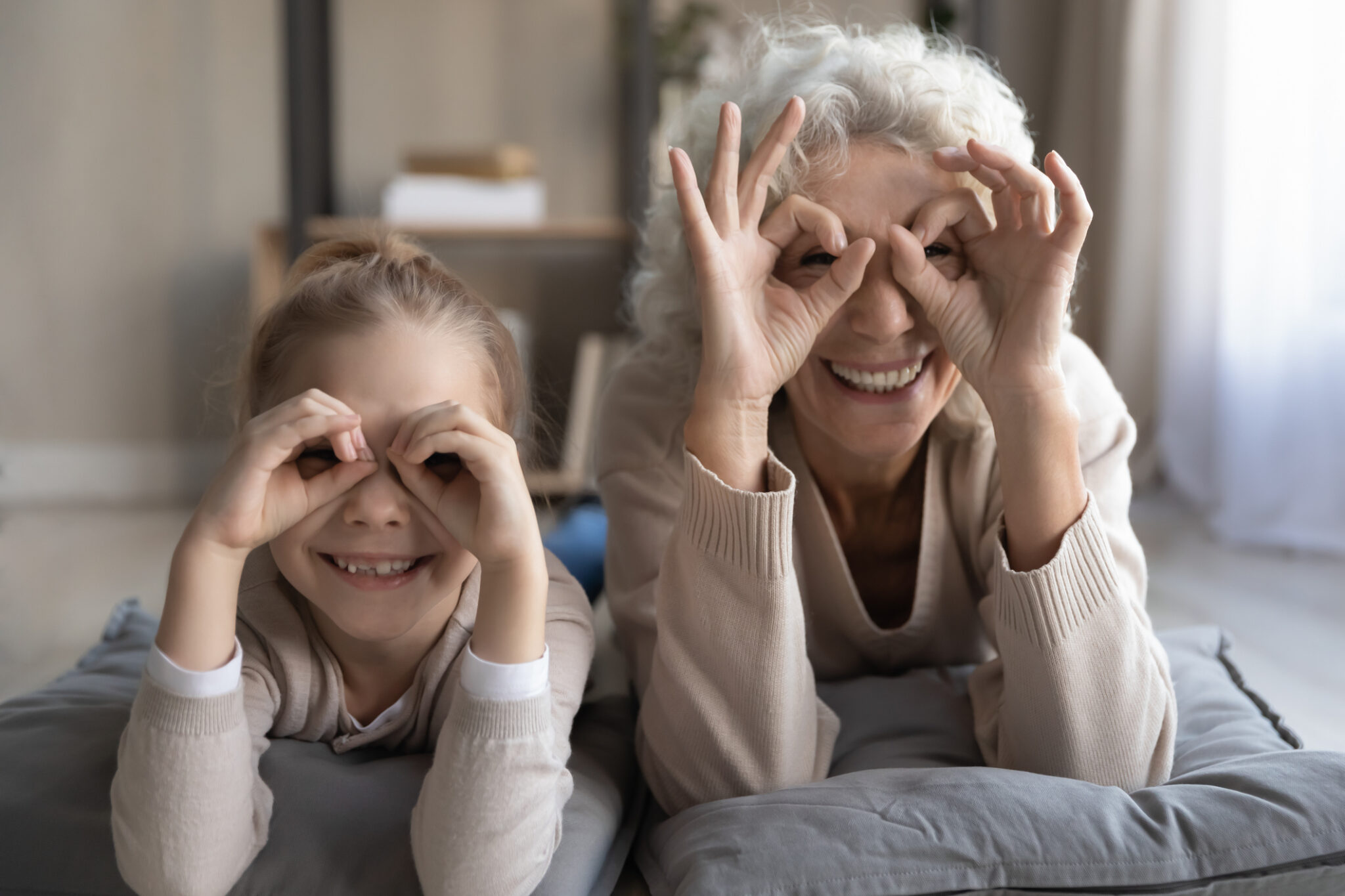 cheerful little girl and senior granny show binoculars of fingers