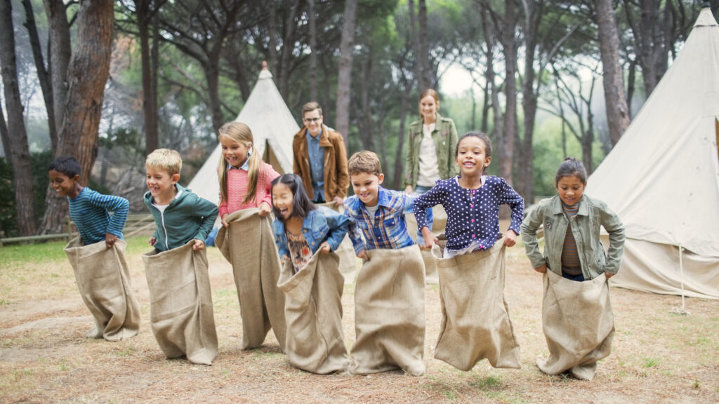 children having sack race at campsite