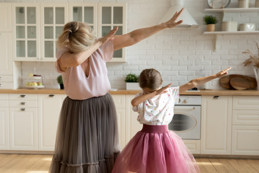 modern grandmother dab dancing with small granddaughter