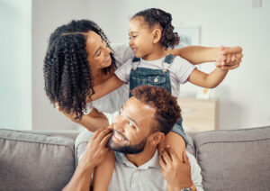 black family or mother, father and child on sofa together for happiness, love and care. happy group of people parents or mom, dad and girl kid on living room couch for home growth development