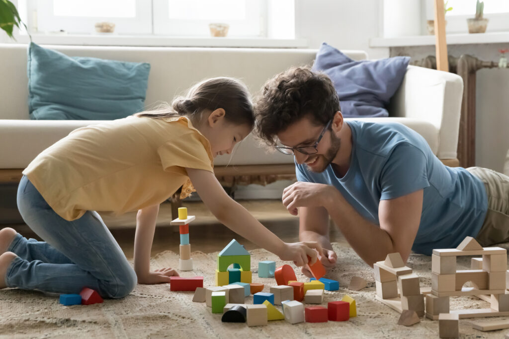 positive engaged young dad and daughter kid playing with cubes