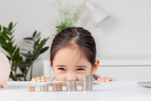 asian little cute girl wearing a cream suit analyzing coins finance and investment