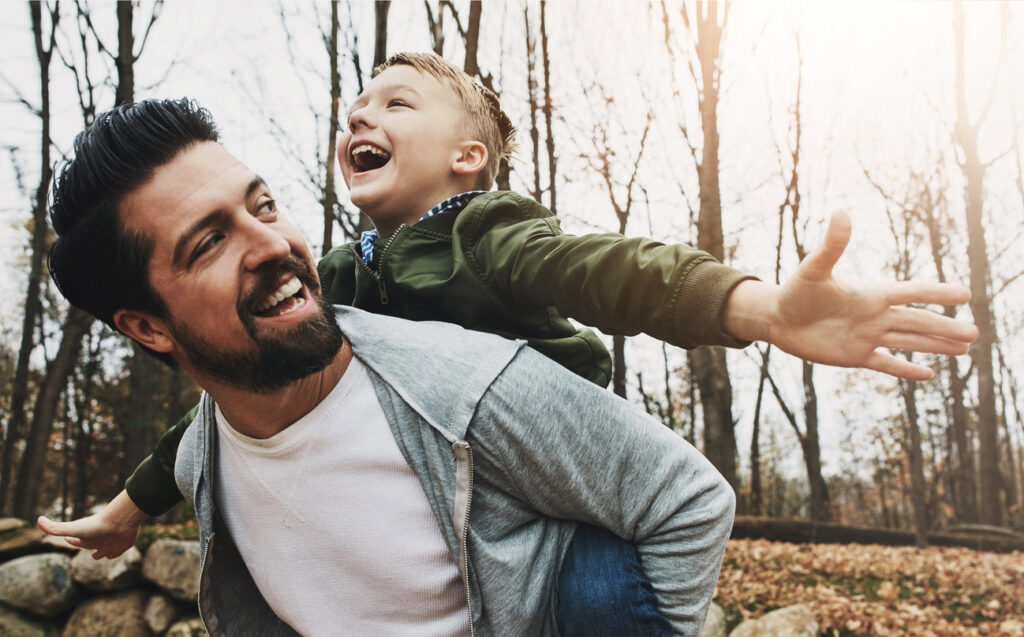 nature, piggyback and father with boy in outdoor park for game, fun and bonding together. forest, playing and happy man with child on back for support, weekend trip or autumn weather in washington