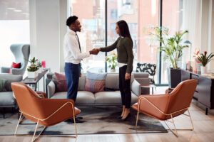 businesswoman shaking hands with male interview candidate in seating area of modern office