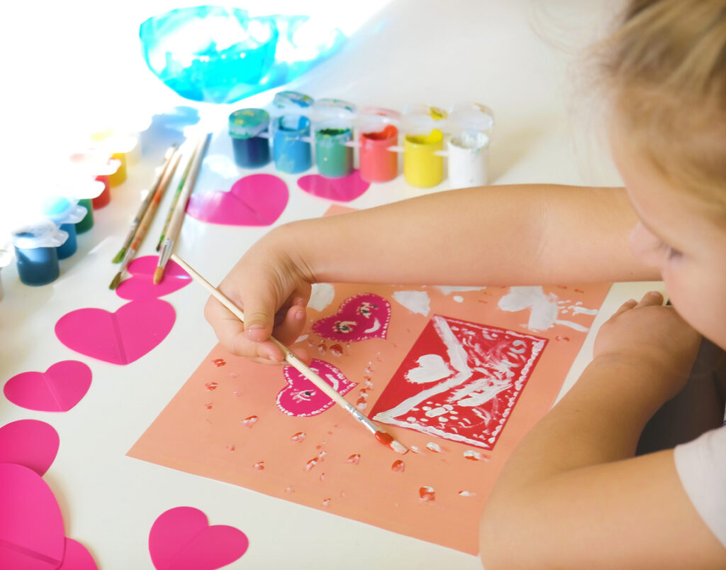 child created homemade greeting card. a little girl painted and colored card with funny hearts. gift for mothers day or valentines day. arts and crafts concept.