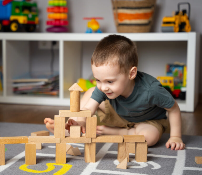little cute toddler boy 2,5 years playing wooden blocks in a home children's room. educational toys for kids. indoors. focus on blocks