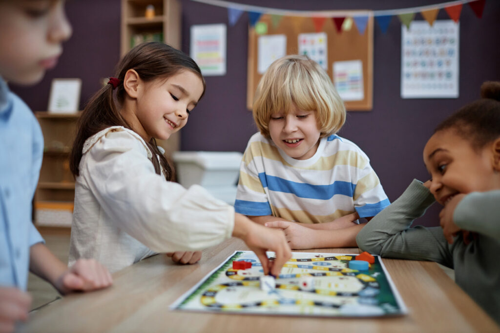 multiethnic group of little children playing board game together