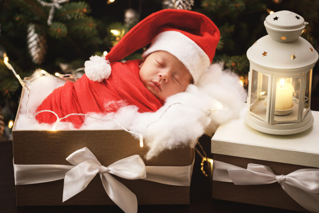 cute newborn baby wearing santa claus hat is sleeping in the christmas gift box