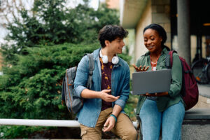 happy university students e learning while using laptop at campus.