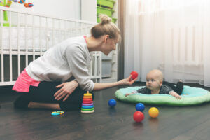 babysitting nanny playing with little baby on the floor at home