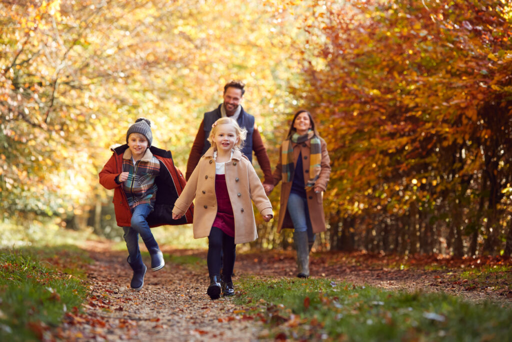 family walking along track in autumn countryside with children running ahead