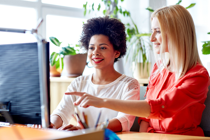happy women or students with computer in office