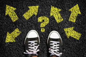 sneakers on an asphalt road. yellow arrows pointing in different directions, and question mark top view. the concept of choosing the right path. business. lifestyle.