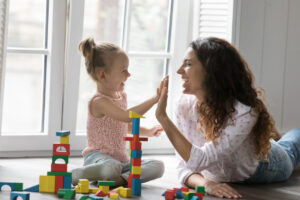 cheerful mom and kid girl clapping hands, giving high five