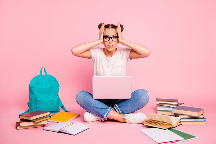 it's too hard! full legs, body, size portrait of confused girl in white t shirt and blue jeans sitting on floor with laptop on knees isolated on bright pink background. deadline concept