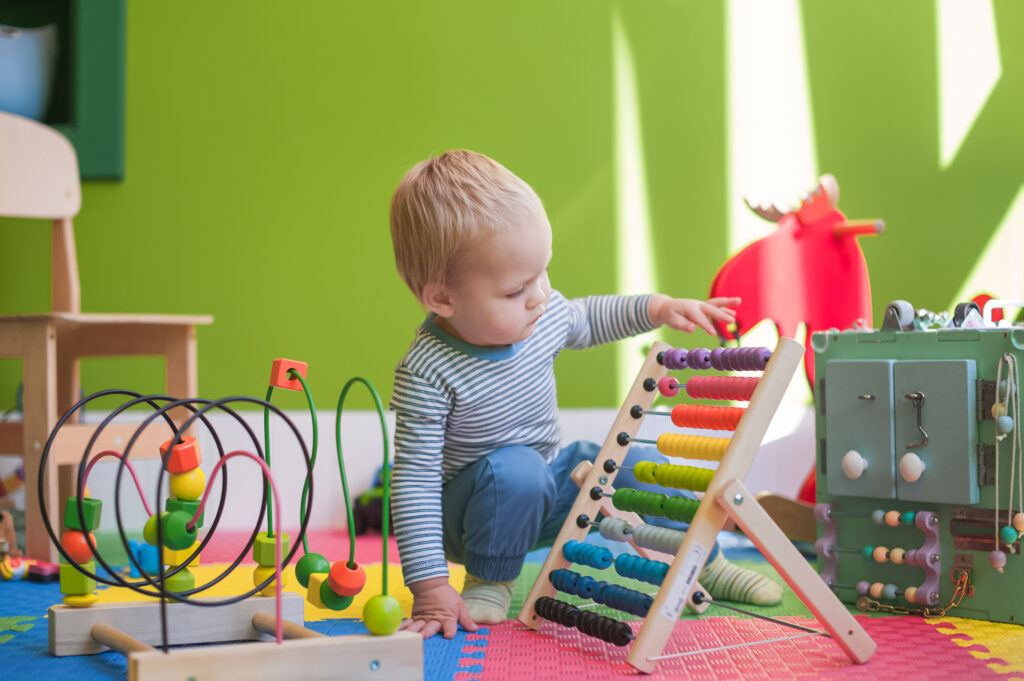 toddler boy plays educational games in playroom..