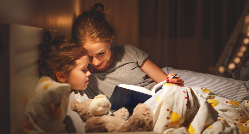 mother and child reading book in bed before going to sleep